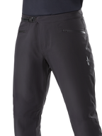 Alpinestars A-Dura wasserdichte Hose, MTB-Hose, Schwarz, Nahaufnahme der Taille mit Ratschensystem und Reißverschlusstaschen, weißes Alpinestars-Logo am Oberschenkel, strapazierfähiges Textil für Fahrten auf nassen Trails