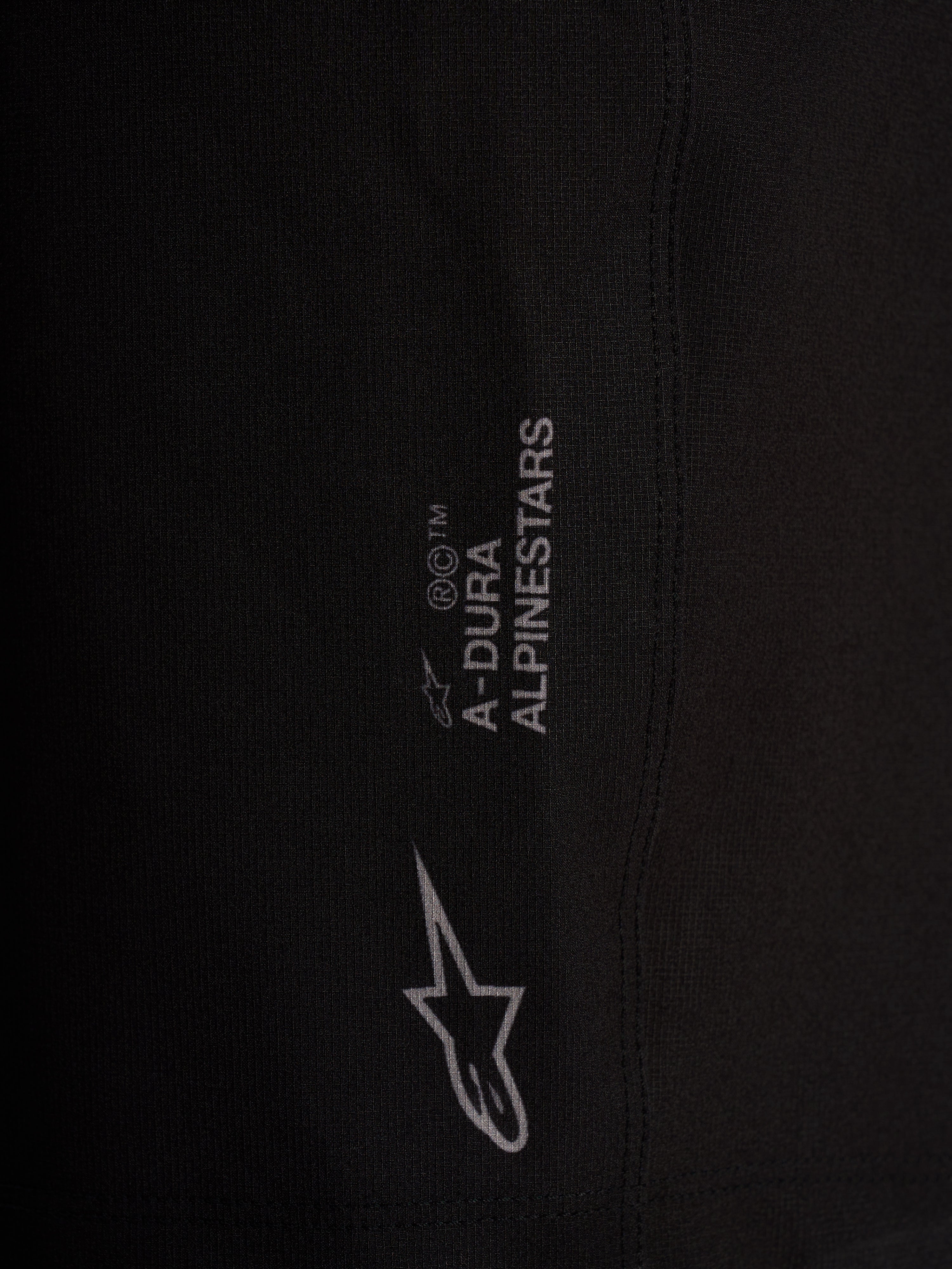 Detail of black Alpinestars A-Dura Ride Liner Shorts with white logos on 4-way stretch performance cycling fabric.