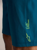 A-Dura Ride MTB Shorts in blue-green, featuring lime green Alpinestars side branding and star logo on stretch woven fabric.