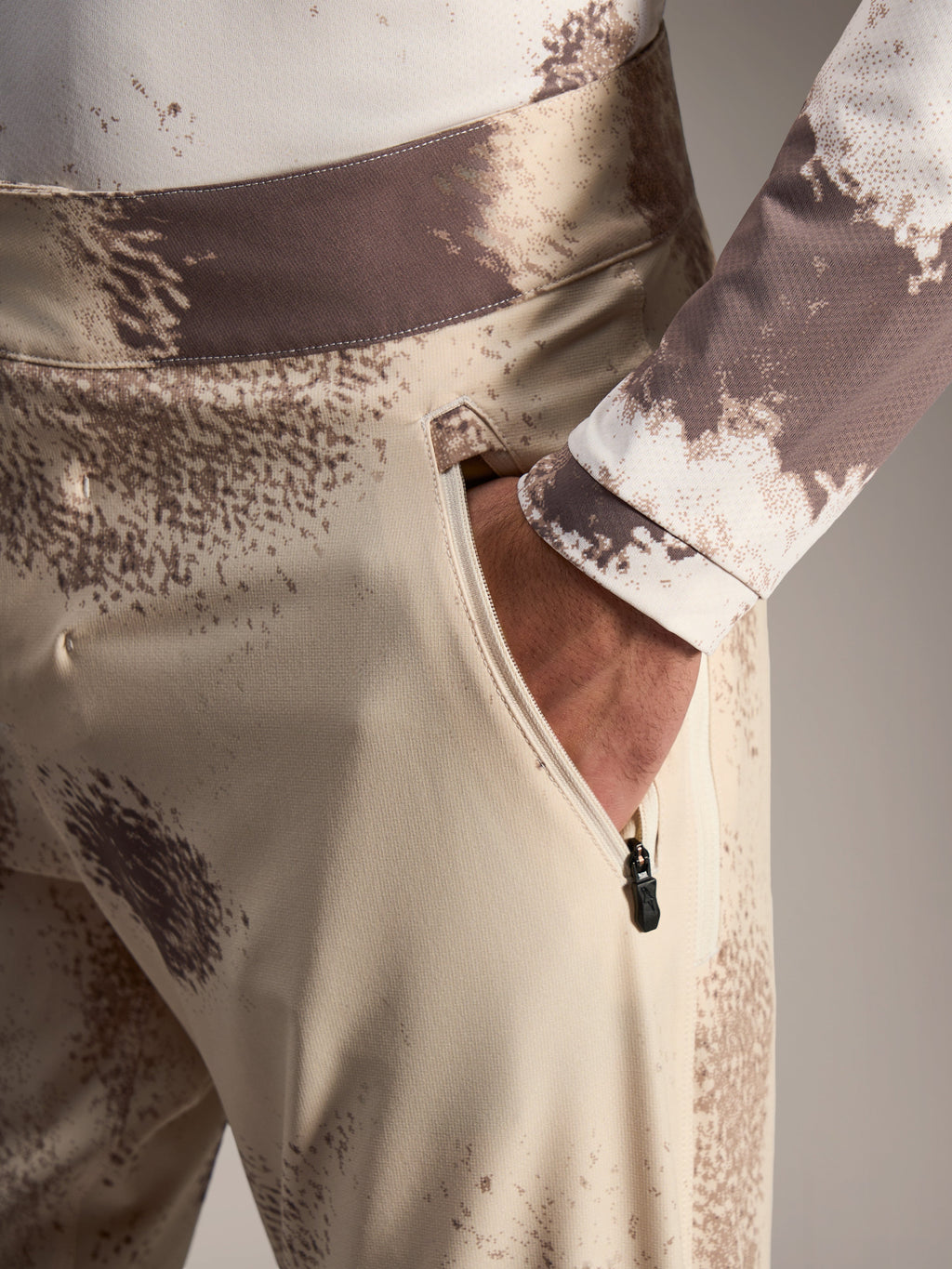 Alpinestars A-Dura Ride Shorts in Sand Camo, showing a zippered side pocket and durable 4-way stretch MTB fabric.