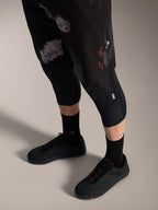 Alpinestars A-Dura Ride Shorts in Black Camo, robuste MTB-Hose mit orangefarbenem Logo, Knieschonern und Radschuhen.
