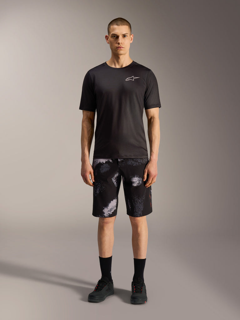 Alpinestars A-Dura Ride Shorts in Black Camo, kombiniert mit einem schwarzen Performance-Shirt für MTB-Vielseitigkeit.