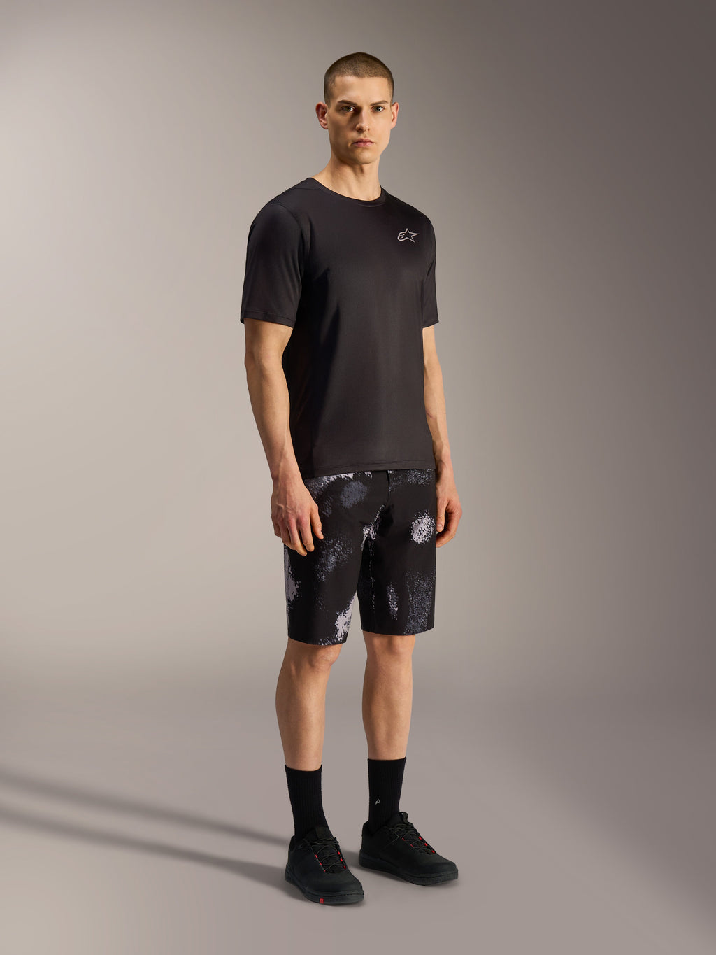 A-Dura Ride MTB-Shorts in Black Camo mit grauem Camouflage-Muster, kombiniert mit schwarzem Jersey und Schuhen.