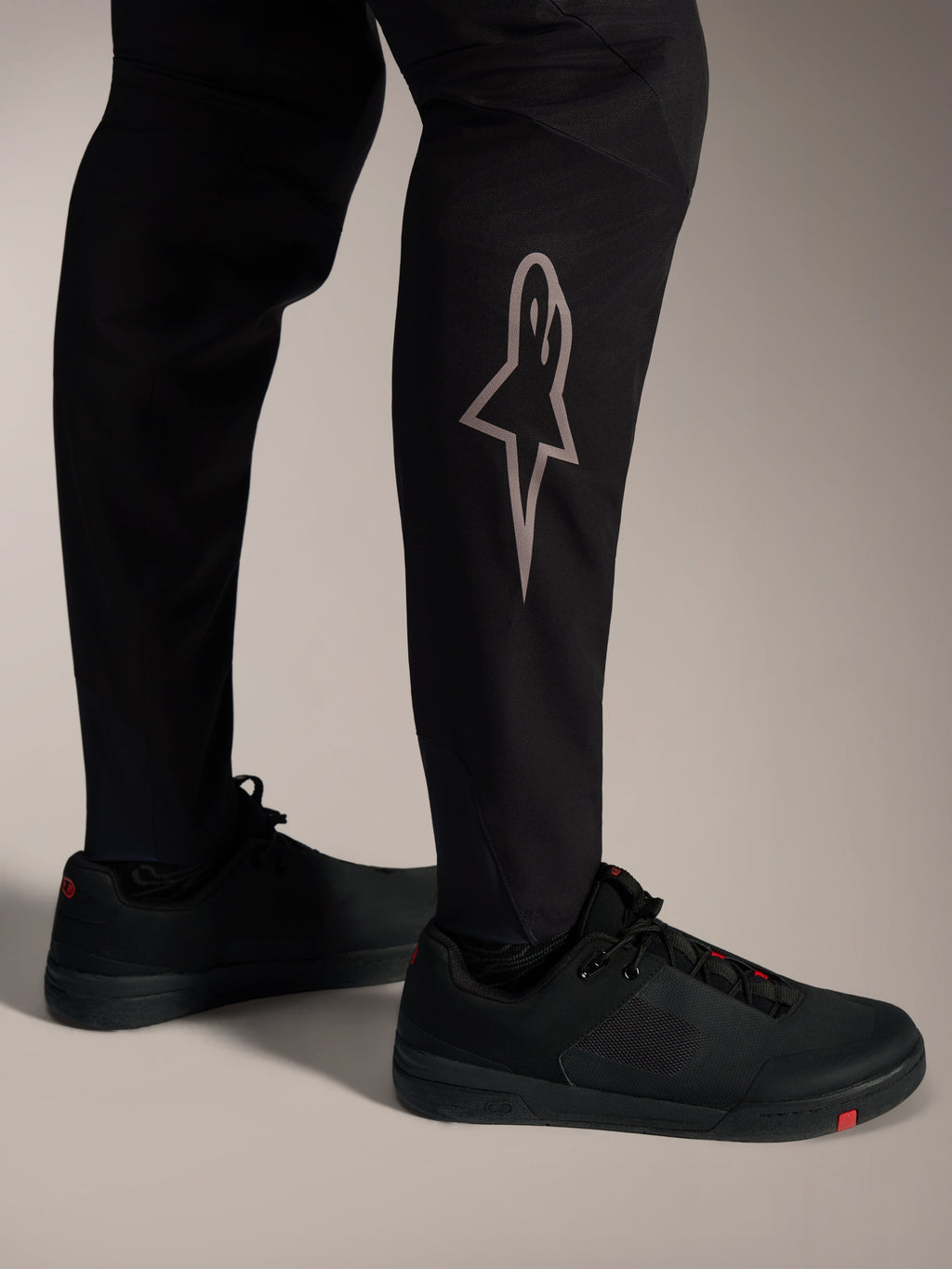 Schwarze A-Supra Elite MTB-Hose mit silbernem Astars-Logo am Unterschenkel, für High-Performance-Mountainbiking.