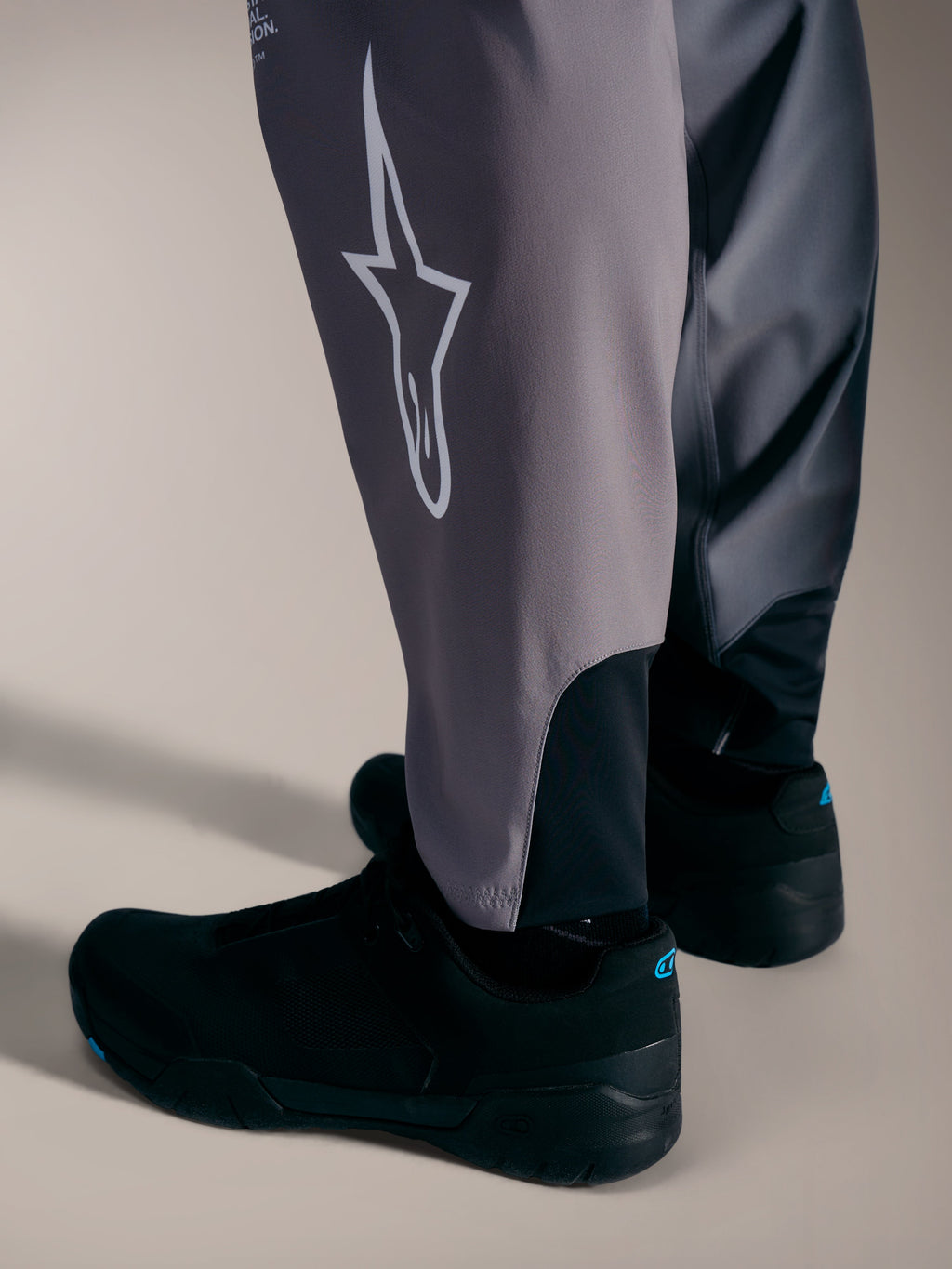 Graue A-Supra Elite Hose mit weißem Astars-Logo und Stretch-Bündchen für Performance-MTB-Rennsport.