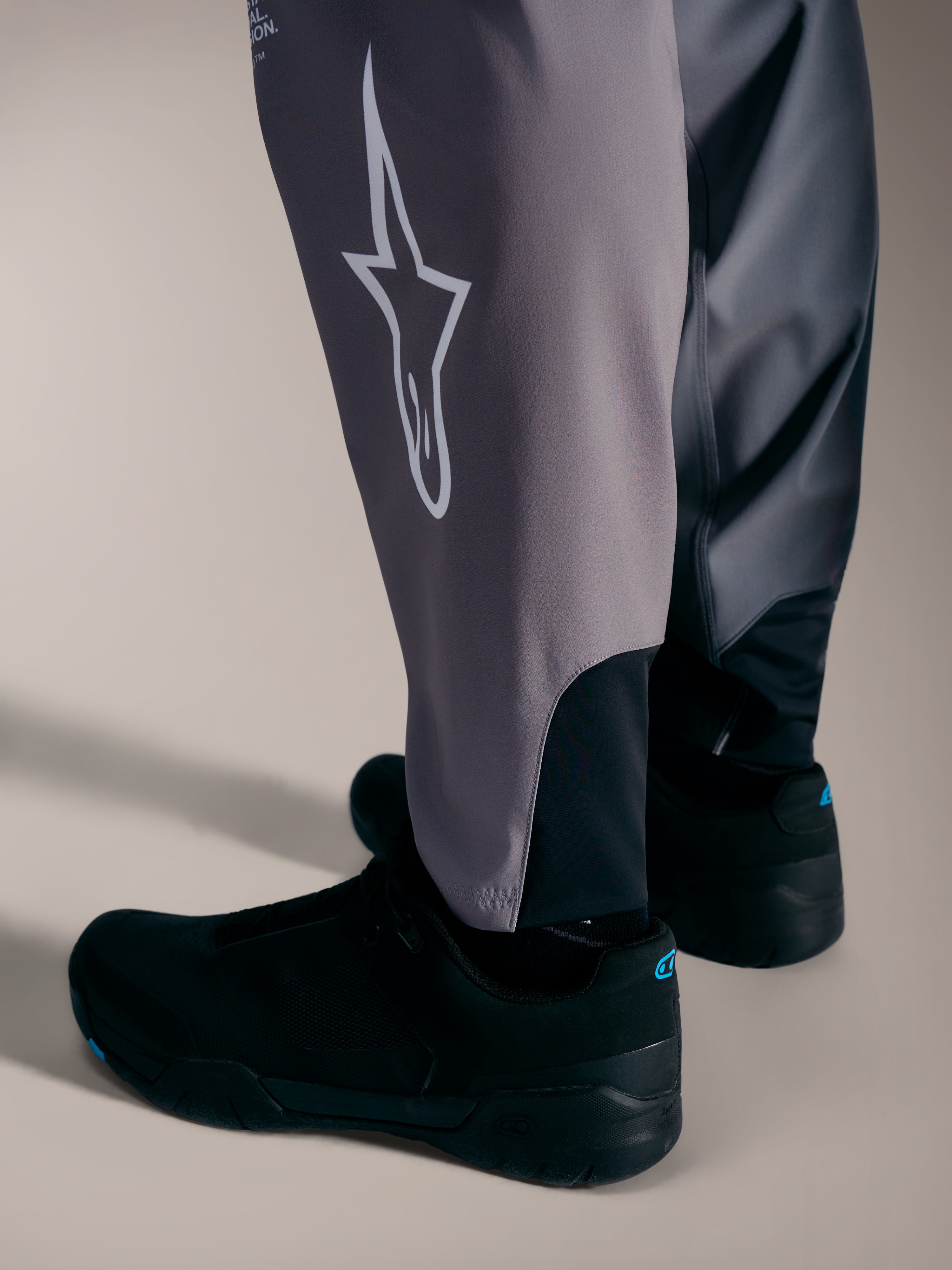 Graue A-Supra Elite Hose mit weißem Astars-Logo und Stretch-Bündchen für Performance-MTB-Rennsport.
