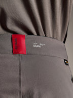 Alpinestars A-Dura Elite Hose, MTB-Hose, Dunkelgrau, Nahaufnahme des Hosenbunds mit einem roten ASTARS-Etikett und weißem DURA-Logo, mit strukturiertem Cordura-Gewebe und hochwertigen Branding-Details.