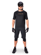 Male mountain bike rider wearing Alpinestars A-Aria Elite Shorts in Black, paired with a matching black Alpinestars short-sleeve jersey, black helmet, gloves, and knee guards, complete off-road cycling gear outfit