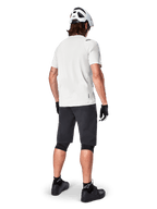 Mountain biker from behind wearing Alpinestars A-Aria Shorts in Black, white performance short-sleeve jersey, white helmet, black gloves, and black mountain bike shoes, cycling gear for trail riding