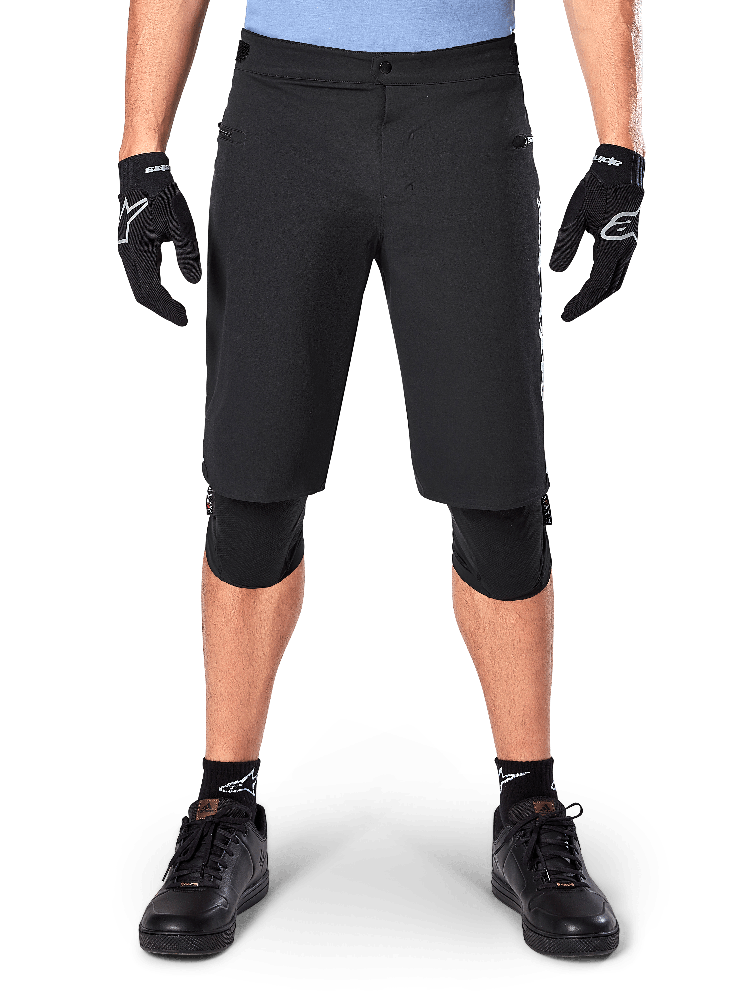 Alpinestars A-Dura Elite Shorts, Black Mountain Bike Shorts, worn by a rider with black gloves and knee pads, featuring front snap closure and zippered pockets, durable Cordura material for off-road cycling