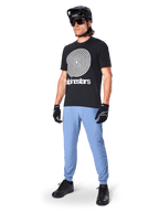 Alpinestars A-Dura Hose, MTB-Hose, Infinity Blue, getragen mit schwarzem Grafik-T-Shirt mit weißem Spiral-Logo, schwarzem Helm, Sonnenbrille und schwarzen Handschuhen, professionelle Mountainbike-Ausrüstung