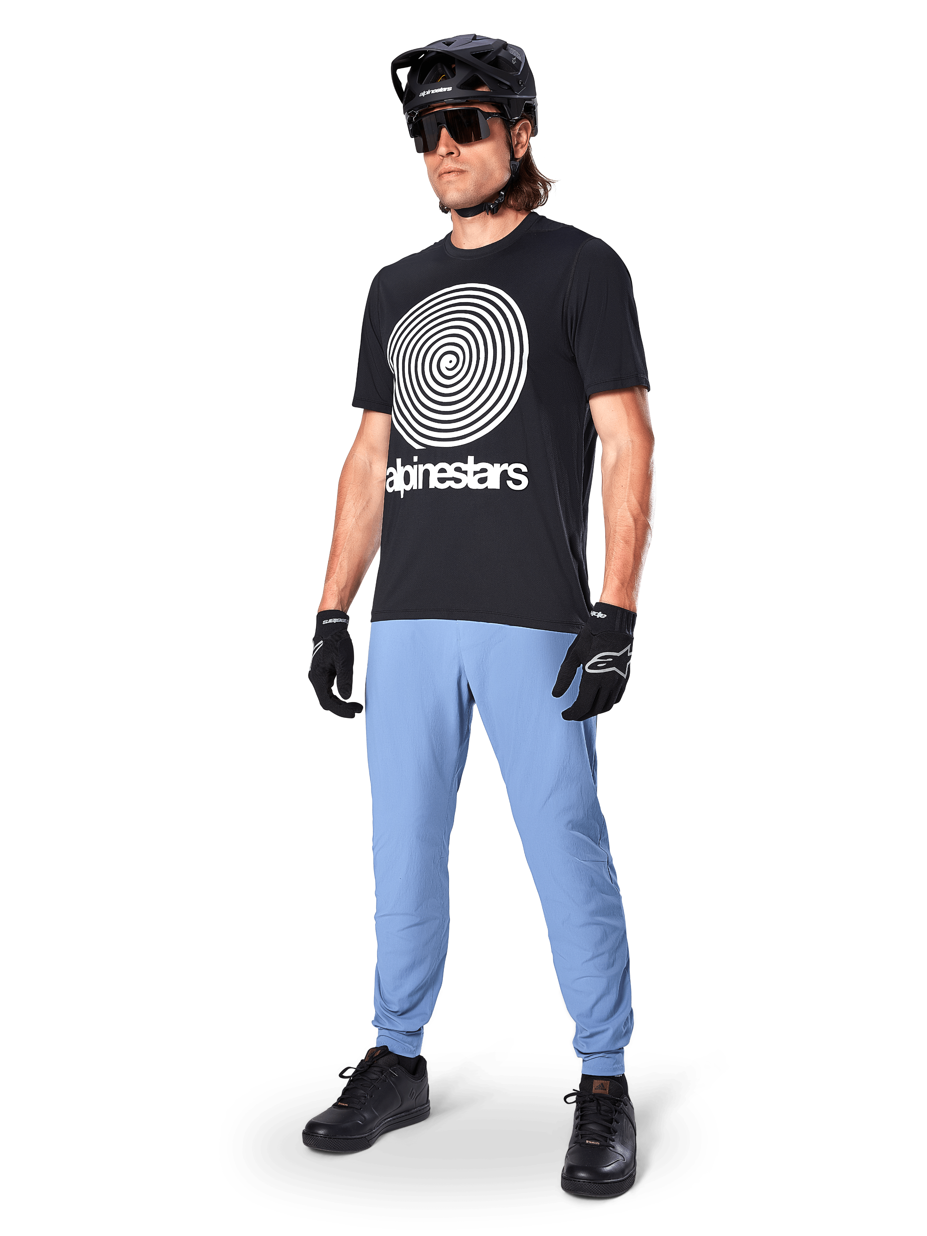 Alpinestars A-Dura Hose, MTB-Hose, Infinity Blue, getragen mit schwarzem Grafik-T-Shirt mit weißem Spiral-Logo, schwarzem Helm, Sonnenbrille und schwarzen Handschuhen, professionelle Mountainbike-Ausrüstung