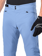 Alpinestars A-Dura Hose, MTB-Fahrradhose, Infinity Blue, Nahaufnahme der Taille mit doppeltem Druckknopfverschluss und seitlichem Taillenversteller, Reißverschlusstaschen, getragen mit schwarzen Alpinestars-Handschuhen