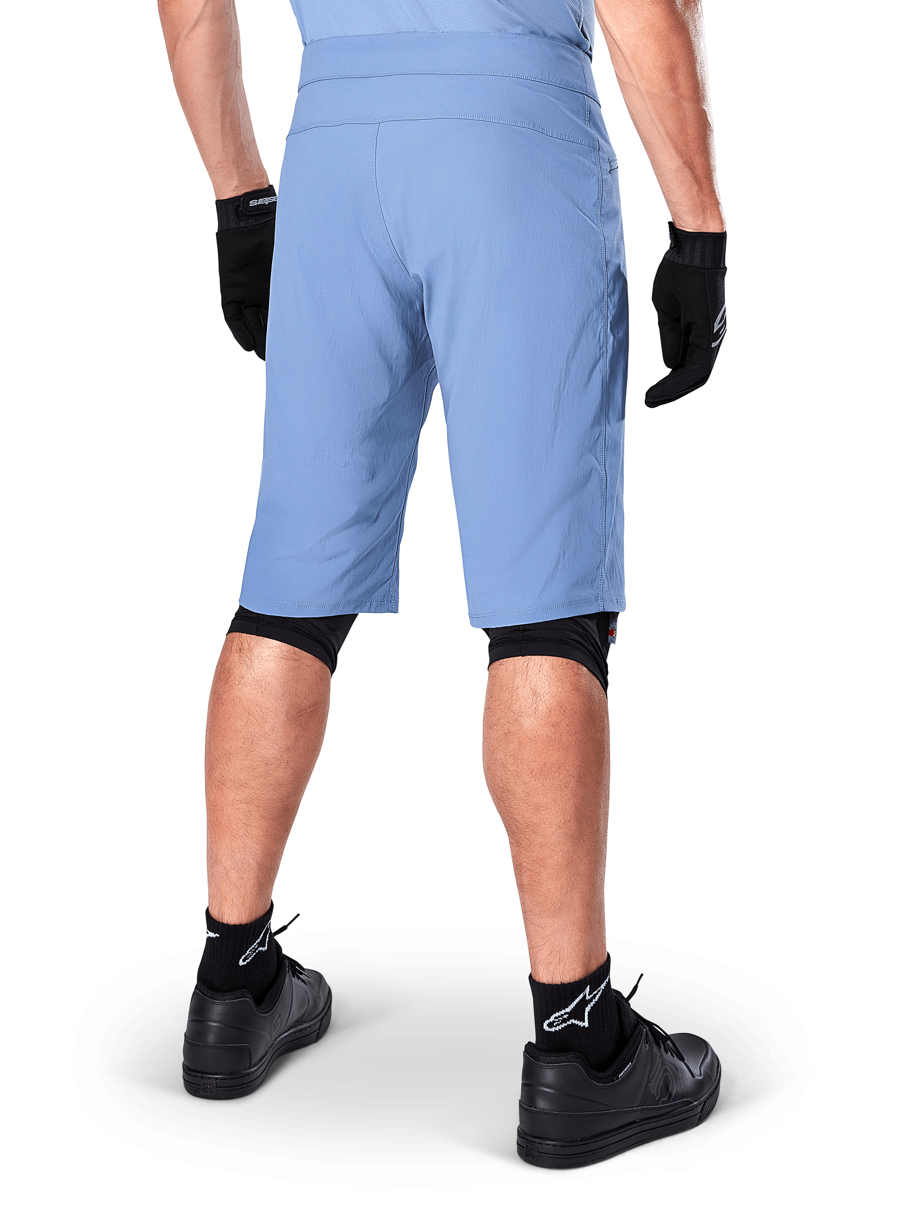 Alpinestars A-Dura Shorts, Mountainbike-Shorts in Infinity Blue, Rückansicht, kombiniert mit schwarzen Handschuhen, Knieschonern und schwarzen Socken mit weißem Stern-Logo, strapazierfähiges Stretch-Material für Offroad-Radsport