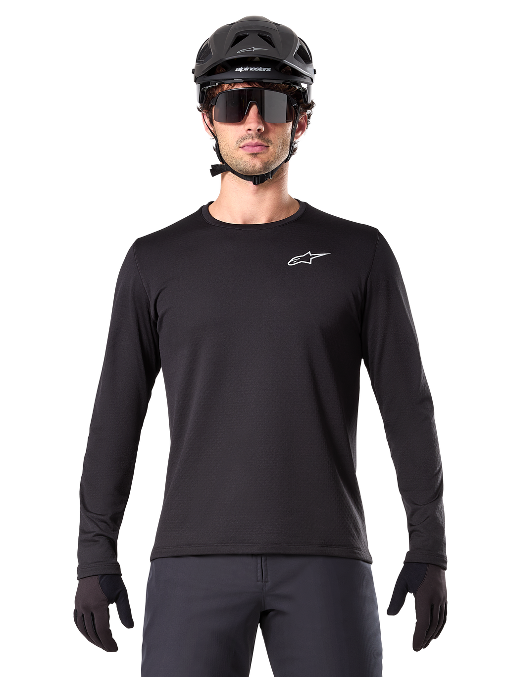 Alpinestars A-Dura Thermal Trikot, schwarzes langärmeliges Mountainbike-Trikot, getragen mit einem schwarzen Helm und einer großen Sonnenbrille, mit kleinem weißen Alpinestars-Logo auf der Brust, reguläre Passform, MTB-Radsportbekleidung