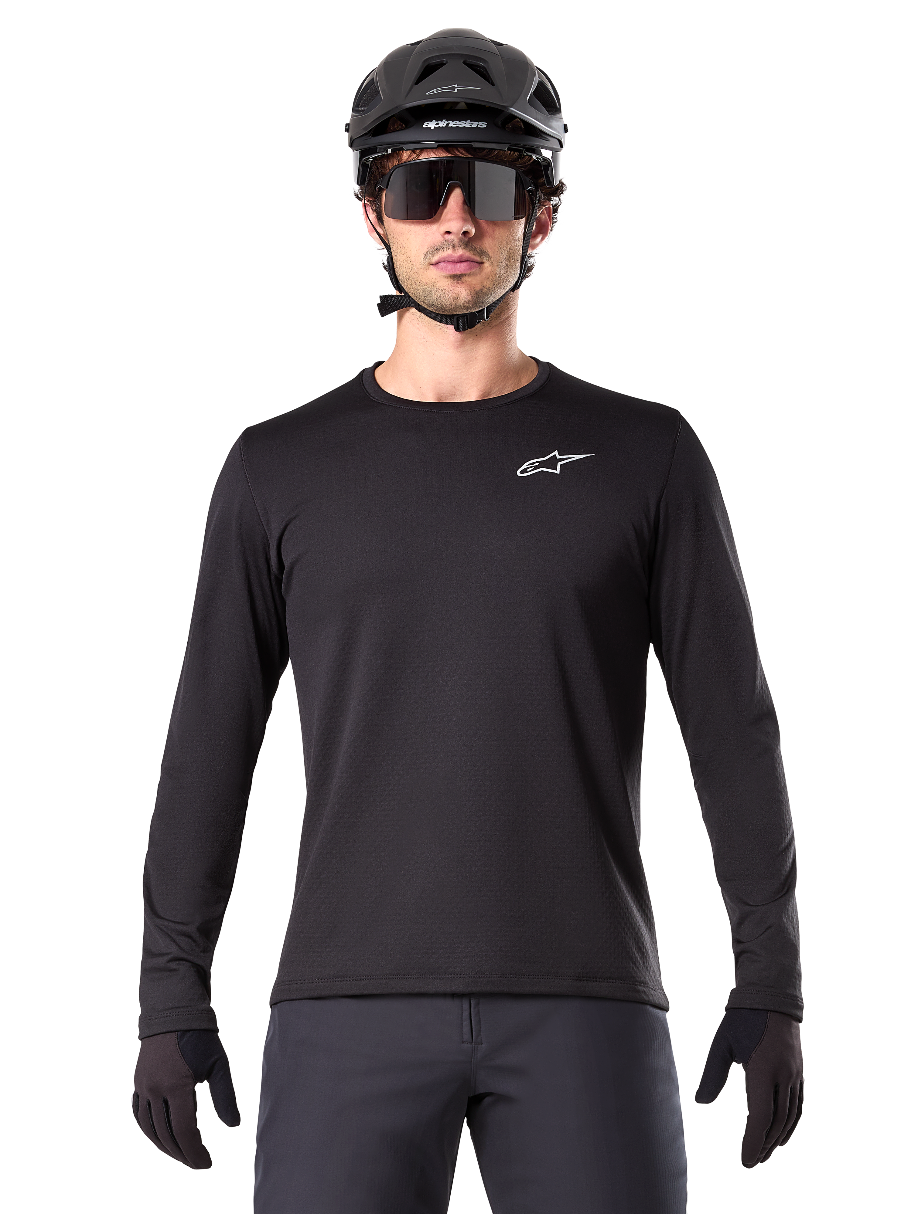 Alpinestars A-Dura Thermal Trikot, schwarzes langärmeliges Mountainbike-Trikot, getragen mit einem schwarzen Helm und einer großen Sonnenbrille, mit kleinem weißen Alpinestars-Logo auf der Brust, reguläre Passform, MTB-Radsportbekleidung