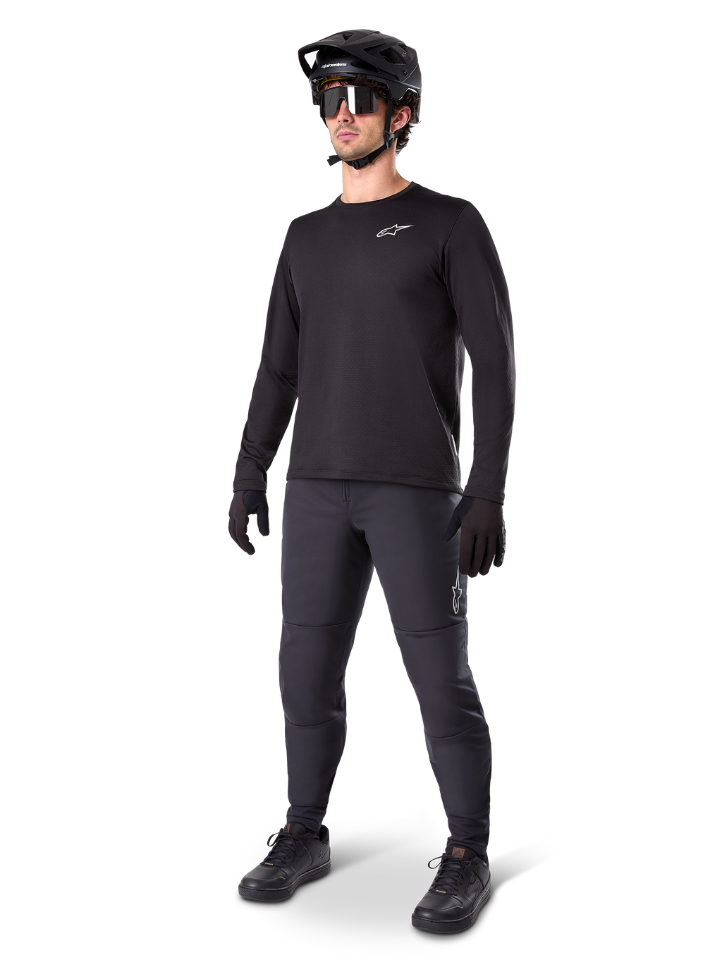 Model trägt Alpinestars A-Dura Thermal Jersey, schwarzes langärmeliges MTB-Trikot, schwarzer Mountainbike-Helm, Sonnenbrille und dunkelgraue Hose, mit kleinem weißen Logo auf der Brust, isolierte Fleece-Konstruktion für Fahrten bei kaltem Wetter