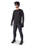 Model trägt Alpinestars A-Dura Thermal Jersey, schwarzes langärmeliges MTB-Trikot, schwarzer Mountainbike-Helm, Sonnenbrille und dunkelgraue Hose, mit kleinem weißen Logo auf der Brust, isolierte Fleece-Konstruktion für Fahrten bei kaltem Wetter