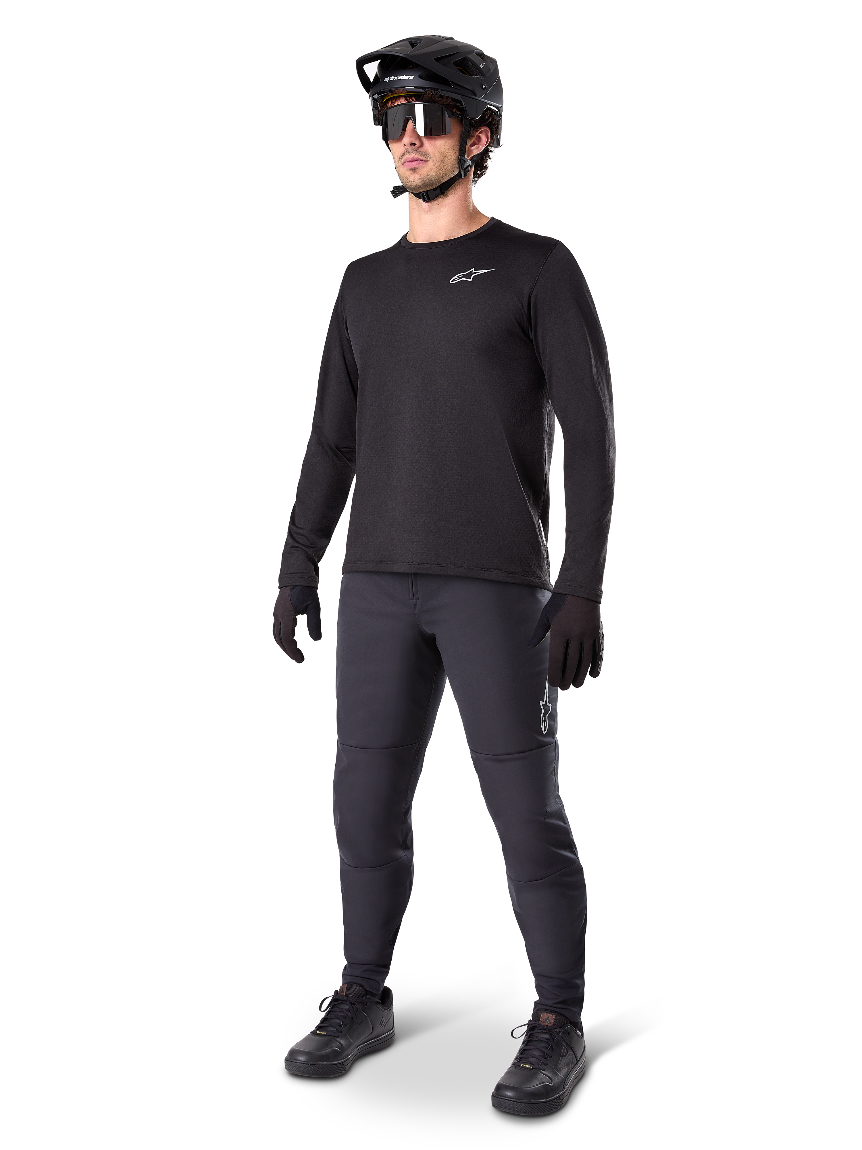 Model trägt Alpinestars A-Dura Thermal Jersey, schwarzes langärmeliges MTB-Trikot, schwarzer Mountainbike-Helm, Sonnenbrille und dunkelgraue Hose, mit kleinem weißen Logo auf der Brust, isolierte Fleece-Konstruktion für Fahrten bei kaltem Wetter