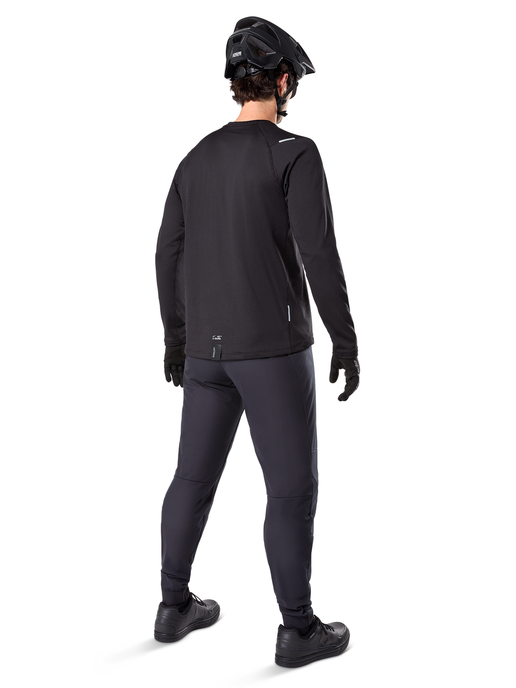 Alpinestars A-Dura Thermal Trikot, langärmeliges Herren-Radtrikot, Schwarz, Rückansicht an einem Model mit schwarzem MTB-Helm, dunkelgrauer Hose und schwarzen Handschuhen, professionelle Mountainbike-Bekleidung für kaltes Wetter