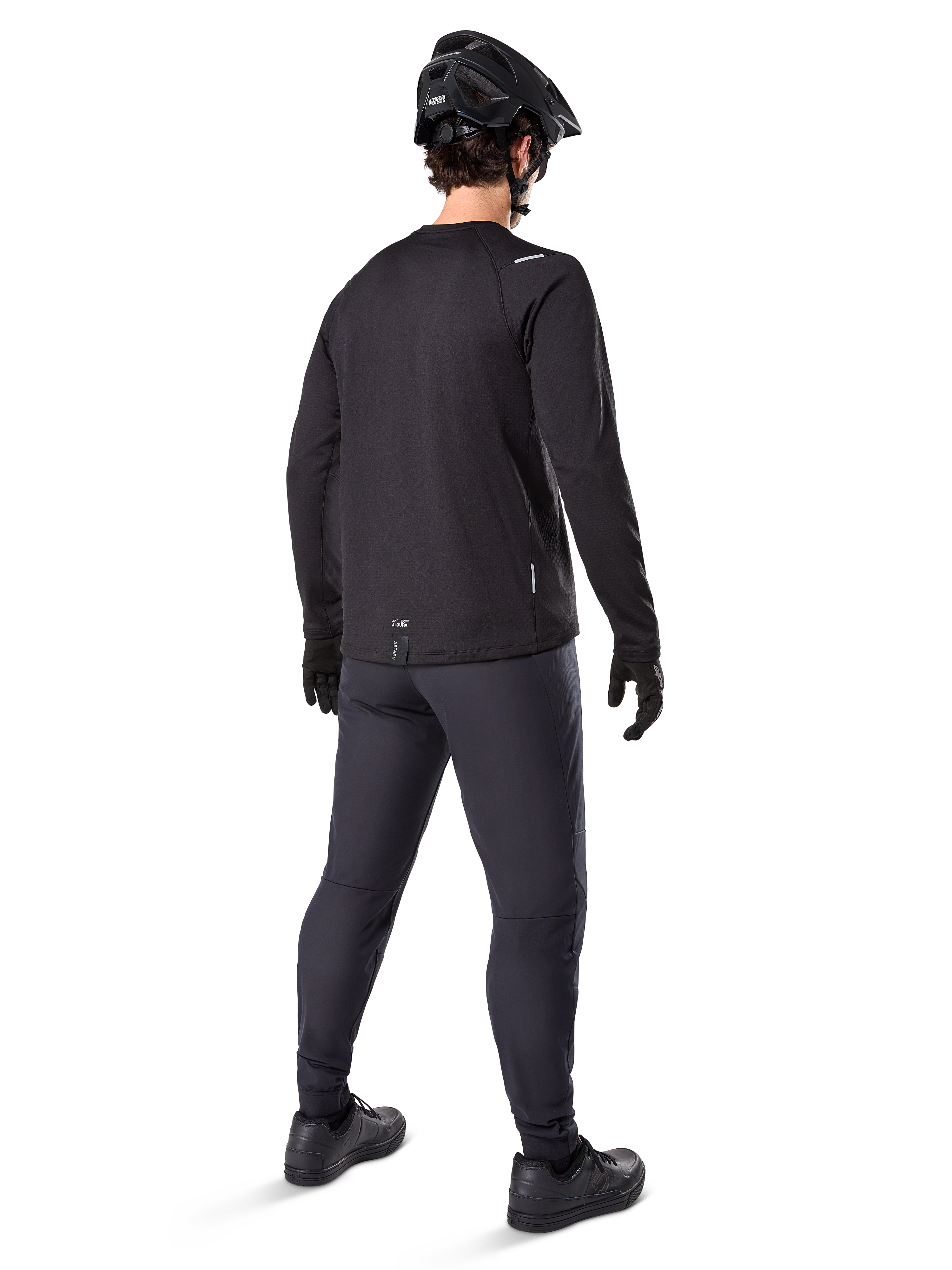 Alpinestars A-Dura Thermal Trikot, langärmeliges Herren-Radtrikot, Schwarz, Rückansicht an einem Model mit schwarzem MTB-Helm, dunkelgrauer Hose und schwarzen Handschuhen, professionelle Mountainbike-Bekleidung für kaltes Wetter