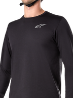 Alpinestars A-Dura Thermal Jersey, Langarm-Radsport-Trikot, Schwarz mit weißem Wortmarken-Logo auf der Brust, isoliertes, fleecegefüttertes Material, verlängertes Rückenteil, konzipiert für Mountainbiking bei kaltem Wetter