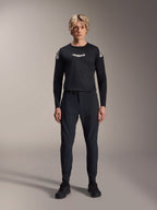 Male model wearing the Alpinestars A-Aria Polartec Elite Long Sleeve Jersey in Black, featuring a white Astars logo on the chest and shoulder branding, paired with black technical MTB pants and shoes, performance mountain bike gear
