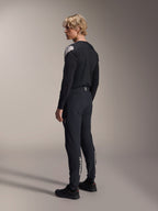 Alpinestars A-Aria Elite Hose, Mountainbike-Hose, Black Titanium, Dreiviertel-Rückansicht am Modell, mit weißem Alpinestars-Branding an den Unterschenkeln, Performance-Passform mit elastischen Bündchen, kombiniert mit einem passenden schwarzen Langarm-Trikot.