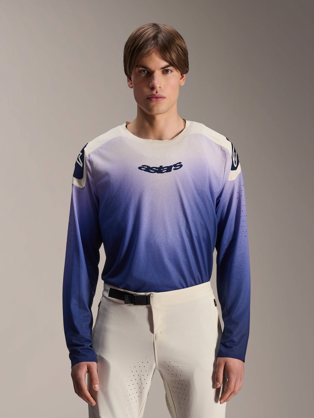 Alpinestars A-Aria Polartec Maker Elite Trikot, Langarm-MTB-Trikot, Baja Blue mit weiß-blauem Farbverlauf, von einem Model mit weißer Hose getragen, mit dunkelblauem Logo auf der Brust und Laserperforationen an den Ärmeln, Performance-Mountainbike-Bekleidung
