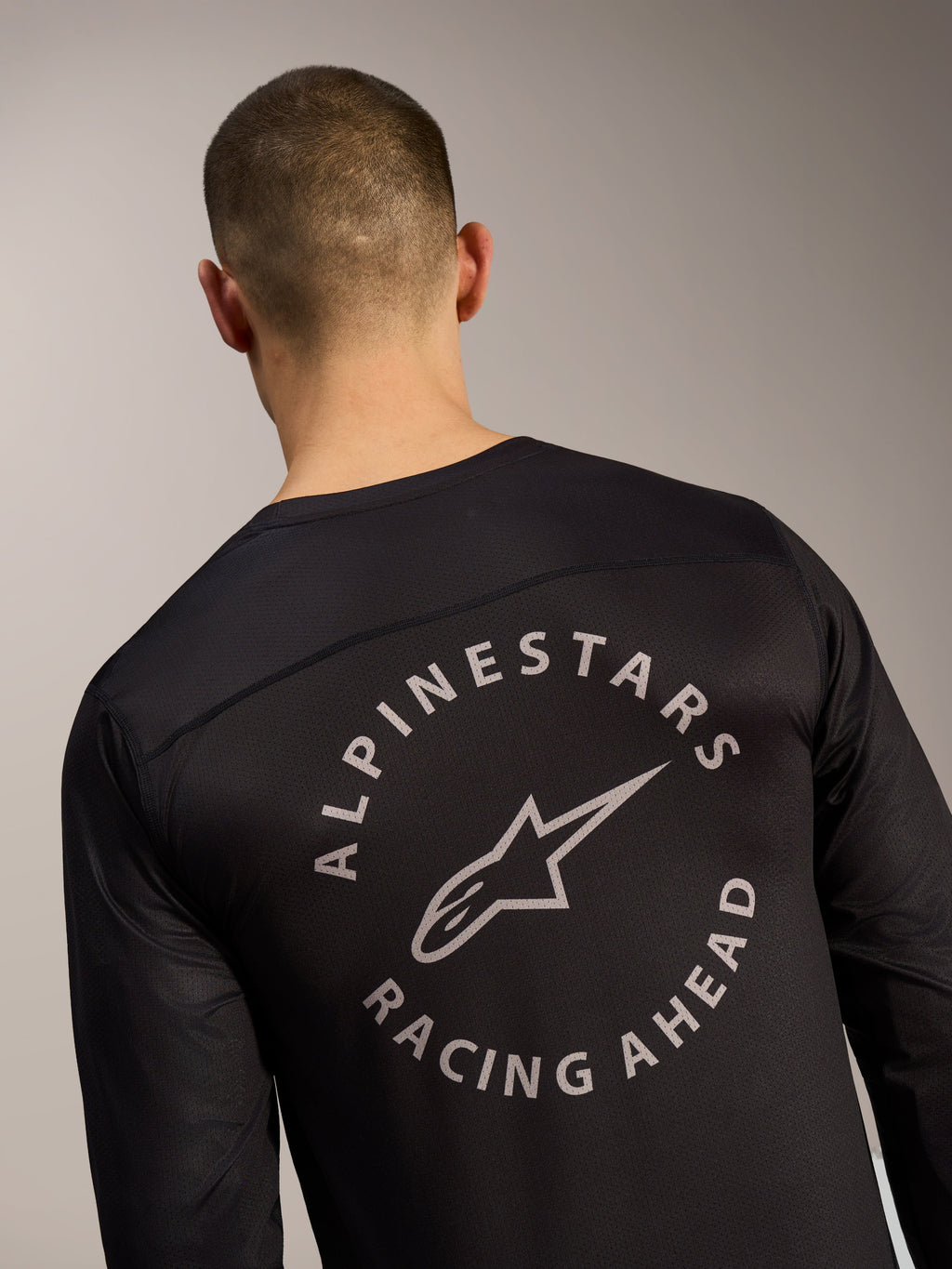 Schwarzes A-Dura Air Trikot, Rückendetail mit kreisförmigem Alpinestars Racing Ahead Logo auf Mesh-Gewebe.