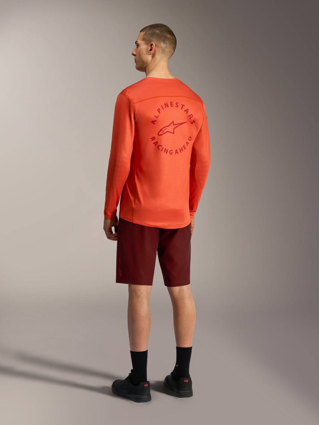 Alpinestars A-Dura Ride Shorts in Bordeaux und oranges A-Dura Air LS Jersey, Rückansicht von MTB-Ausrüstung.