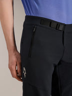 Alpinestars A-Aria Elite Shorts, Mountainbike-Shorts, Black Titanium, mit magnetischem Schnallenverschluss, Reißverschlusstasche und weißem Alpinestars-Logo, getragen mit einem blauen Radtrikot, Performance-Mountainbike-Ausrüstung