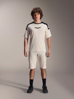 Alpinestars A-Aria Elite Shorts, Mountainbike-Shorts, Ecru, getragen mit passendem Kurzarmtrikot mit schwarzen Schultereinsätzen und Logo, lässiger sportlicher Look mit Perforationen auf der Vorderseite, Performance-MTB-Bekleidung