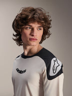 Alpinestars A-Aria Polartec Elite Kurzarm-Trikot, Ecru mit schwarzen Schultereinsätzen, mit schwarzem Astars-Logo auf der Brust und weißem Astars-Logo auf der Schulter, leistungsstarke Mountainbike-Bekleidung, getragen von einem Modell