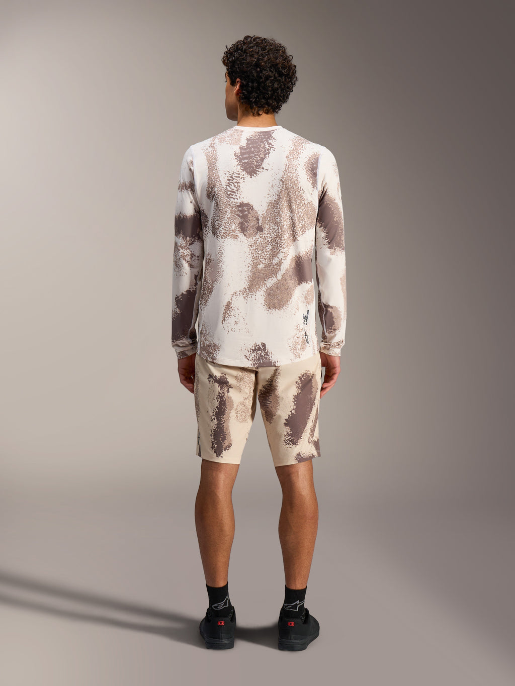Alpinestars A-Dura Ride LS Jersey and matching shorts in sand camo pattern, styled as a complete MTB outfit, rear view.