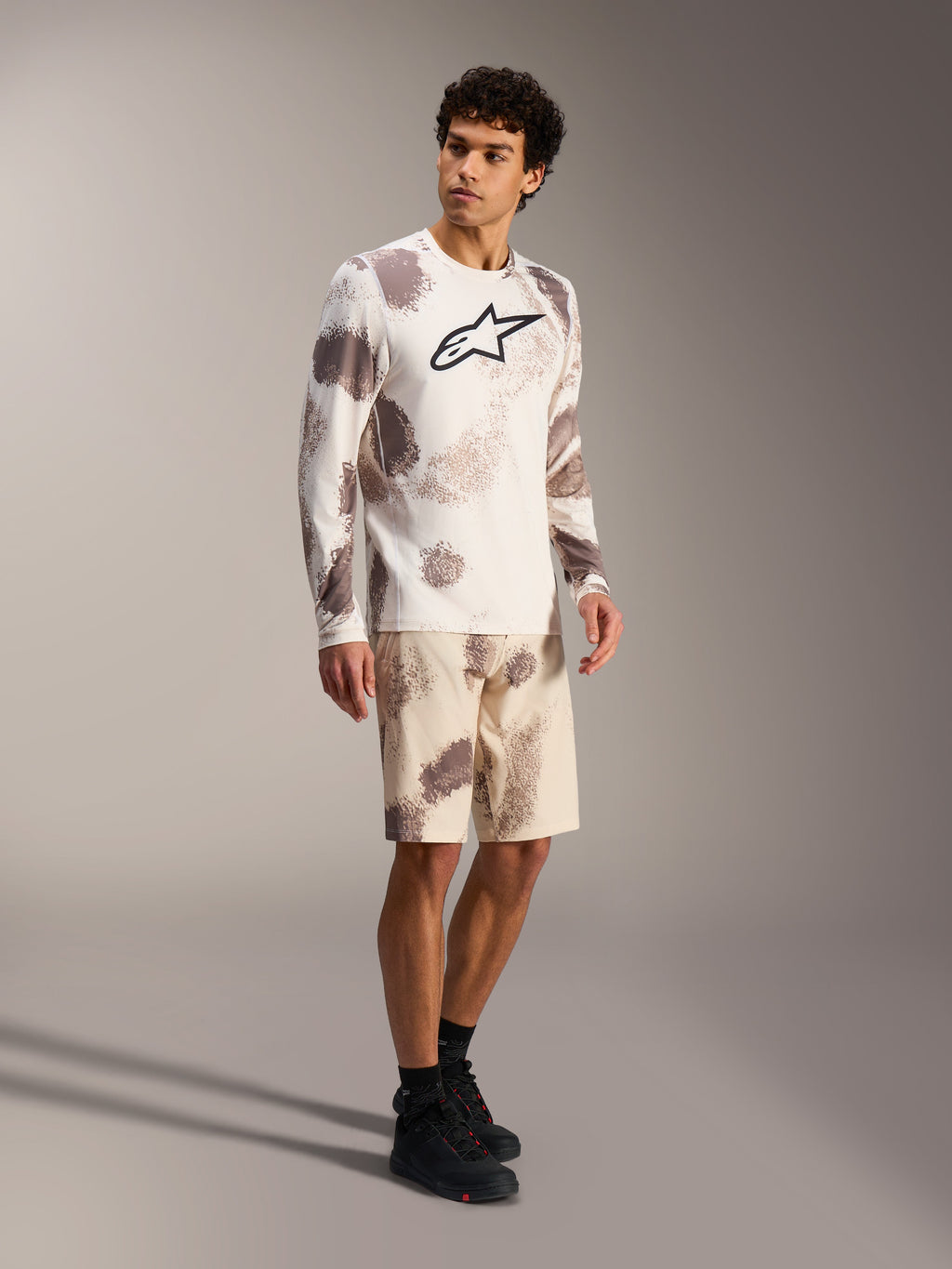 A-Dura Ride Langarm-Trikot in Sand Camo, MTB-Ausrüstung mit markantem Brustlogo und passenden gemusterten Shorts.