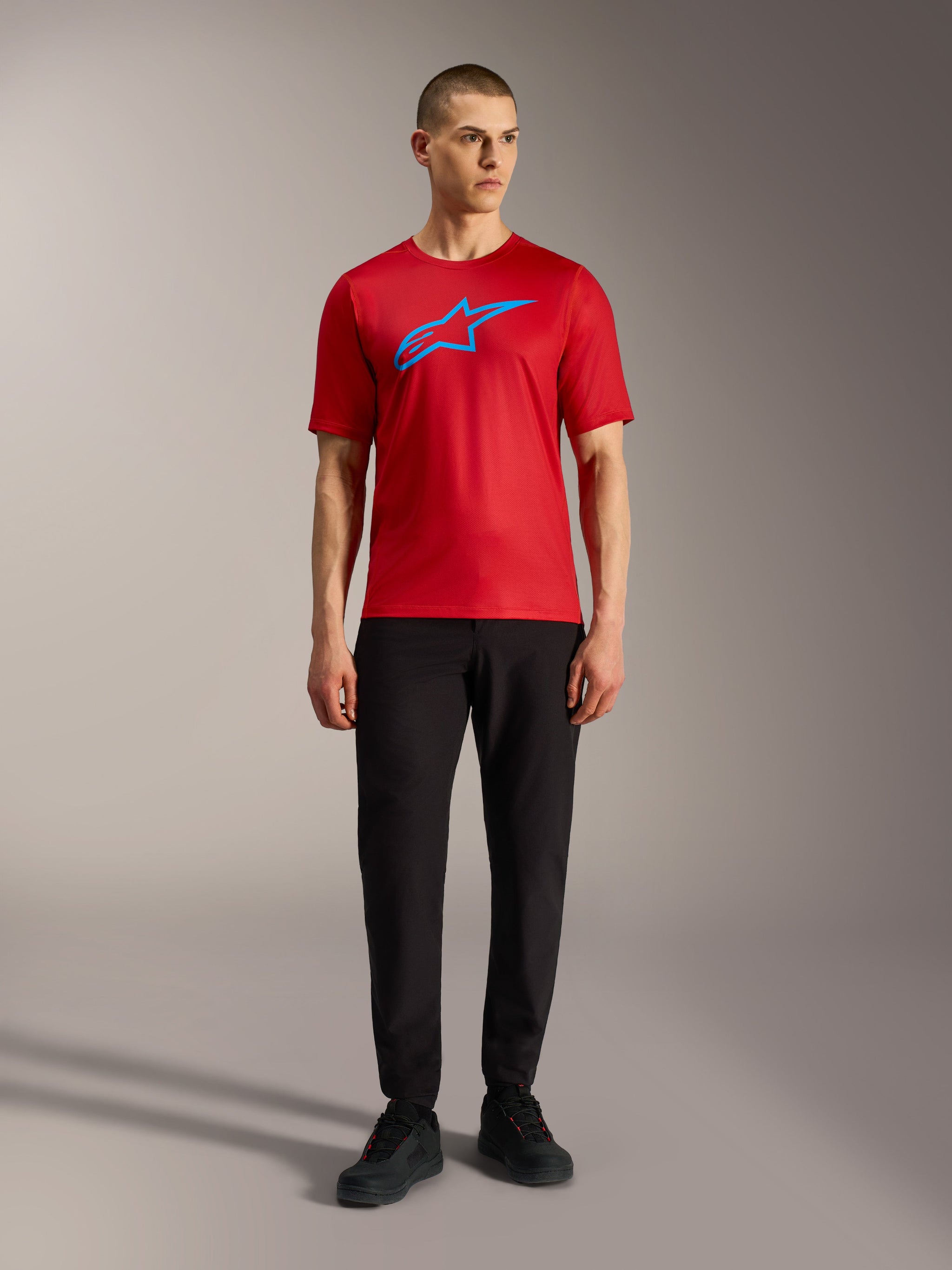 Rotes Alpinestars A-Dura Ride Trikot mit blauem Logo und schwarzer Hose, lässiger Mountainbike-Look.