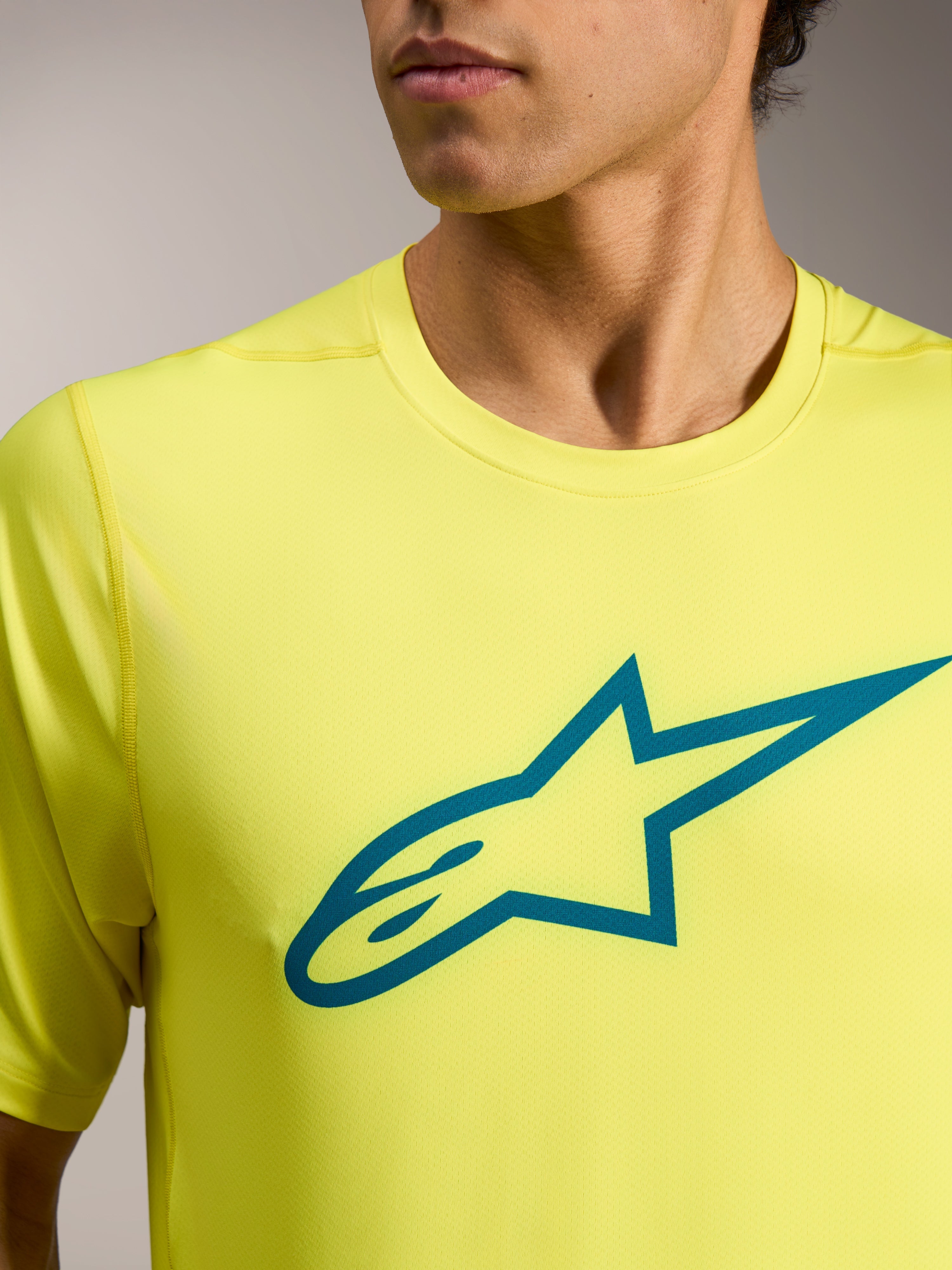 Gelb fluoreszierendes A-Dura Ride Kurzarmtrikot mit blaugrünem Astars-Logo auf der Brust, technische MTB-Bekleidung.