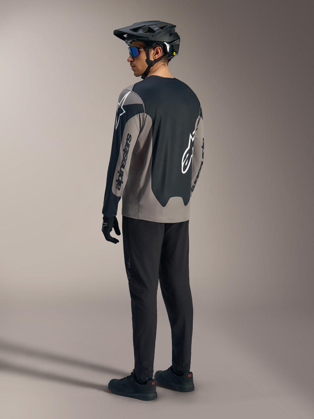 Grau-schwarzes A-Dura Race Langarmtrikot von Alpinestars, Rückansicht in kompletter Mountainbike-Ausrüstung.