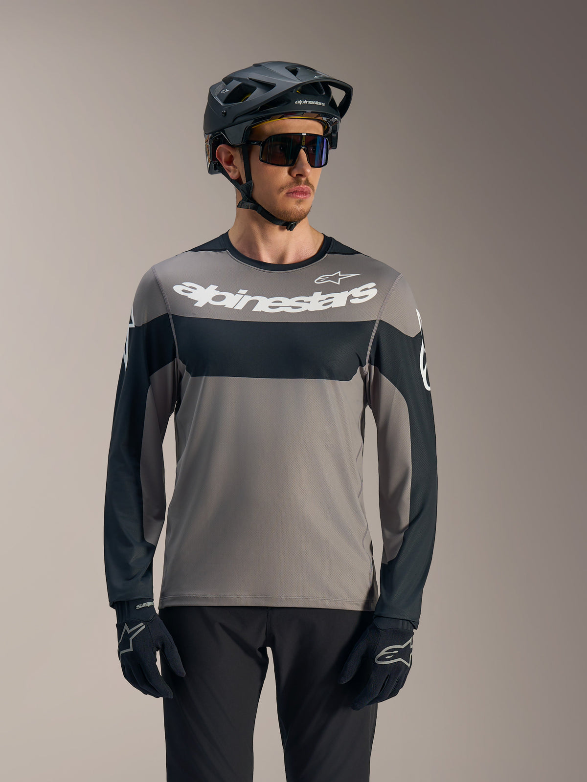 A-Dura Race Langarmtrikot in Grau und Schwarz, weißes Alpinestars-Logo, MTB-Look mit Helm für Trail-Fahrten.