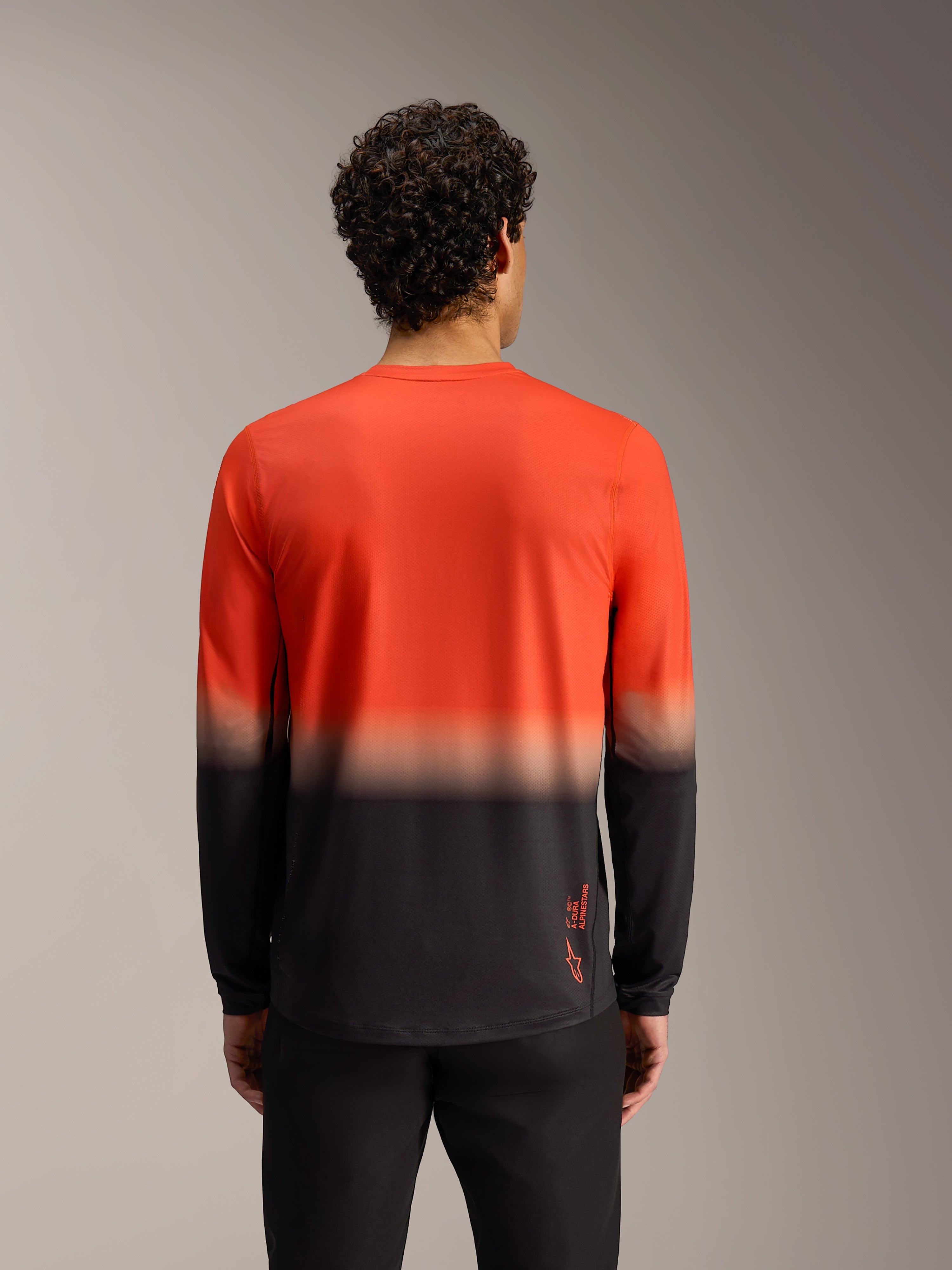 Alpinestars A-Dura ASTARS 2.0 Langarmtrikot, orange-schwarzer Farbverlauf, Rückansicht funktionaler MTB-Ausrüstung.