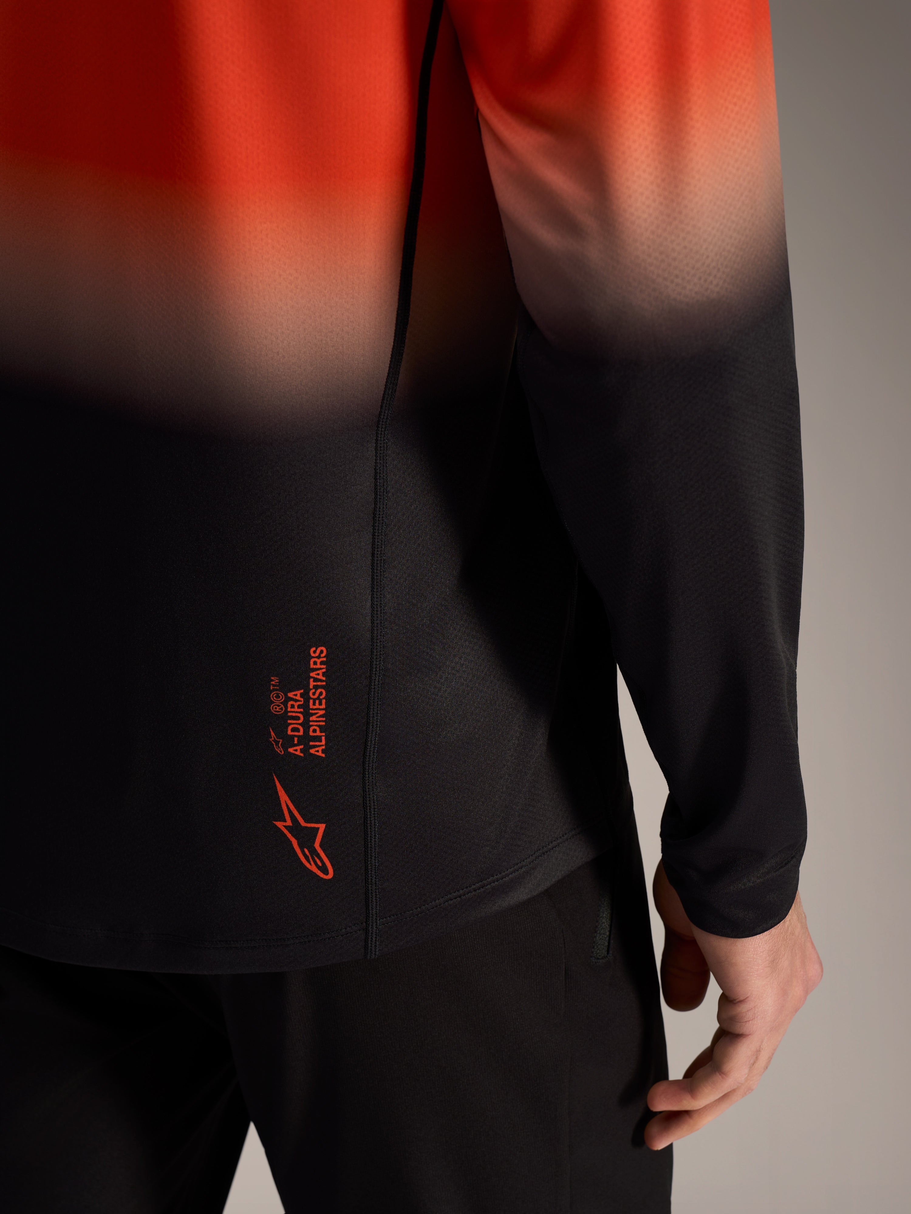A-Dura ASTARS Jersey 2.0 mit orange-schwarzem Farbverlauf, Logo am unteren Rücken und Jacquard-Material.