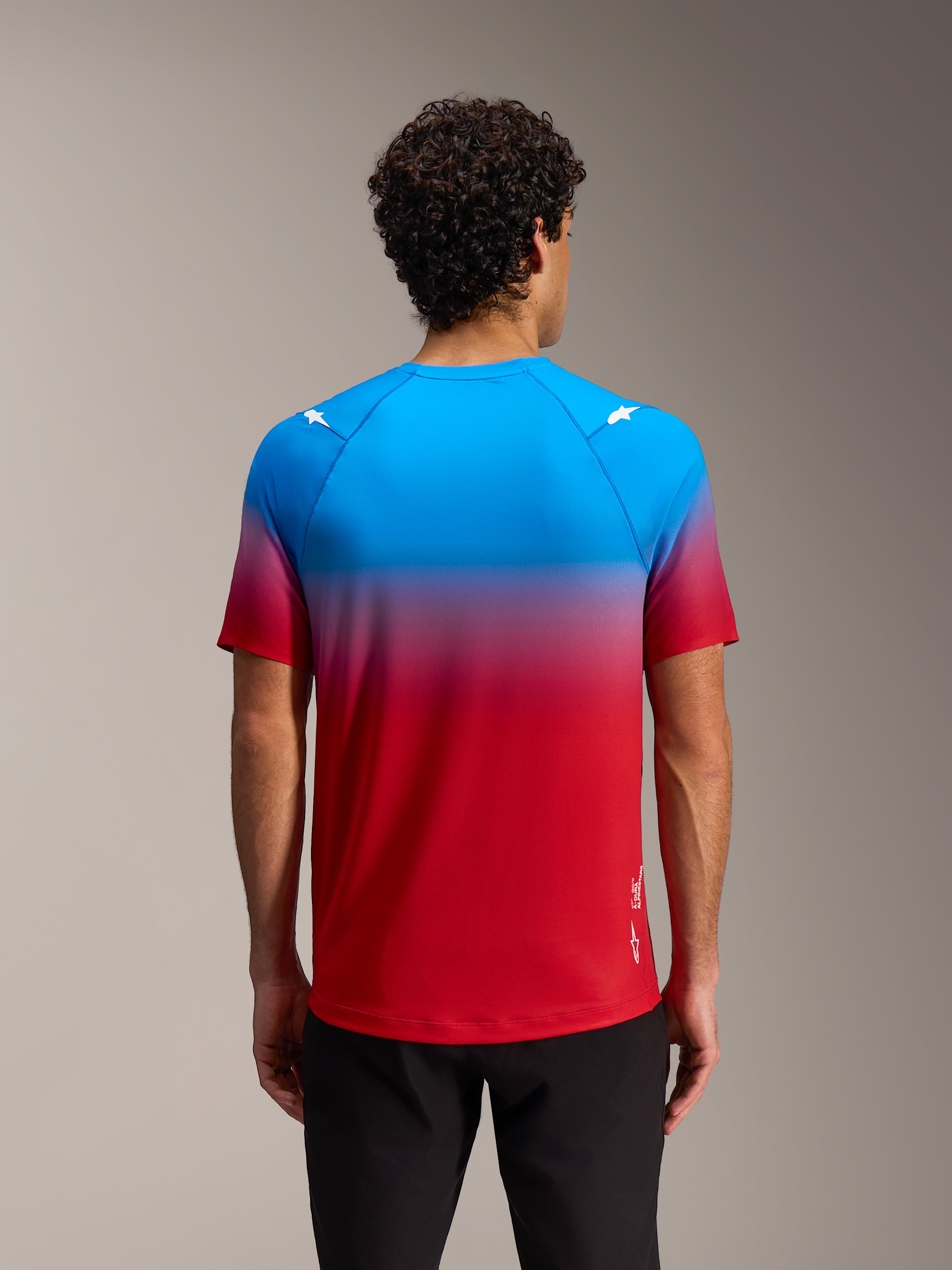 Alpinestars A-Dura ASTARS 2.0 Kurzarmtrikot, rot-blauer Farbverlauf mit Stern-Logos auf den Schultern, Rückansicht.