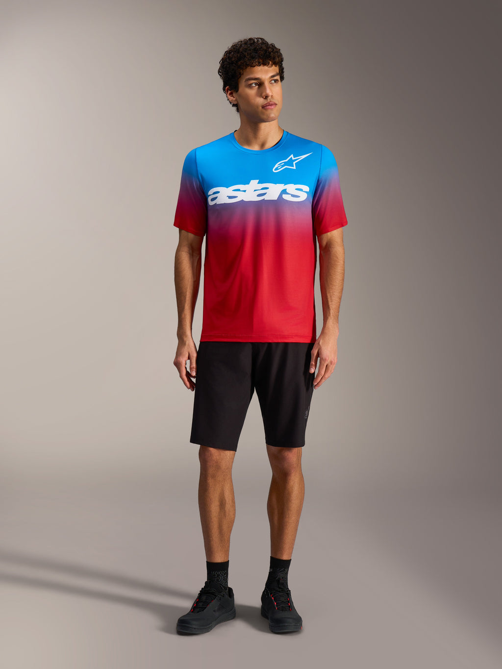 A-Dura ASTARS Jersey 2.0 in Hellrot-Blau mit weißem Logo, kombiniert mit schwarzen MTB-Shorts und Schuhen.