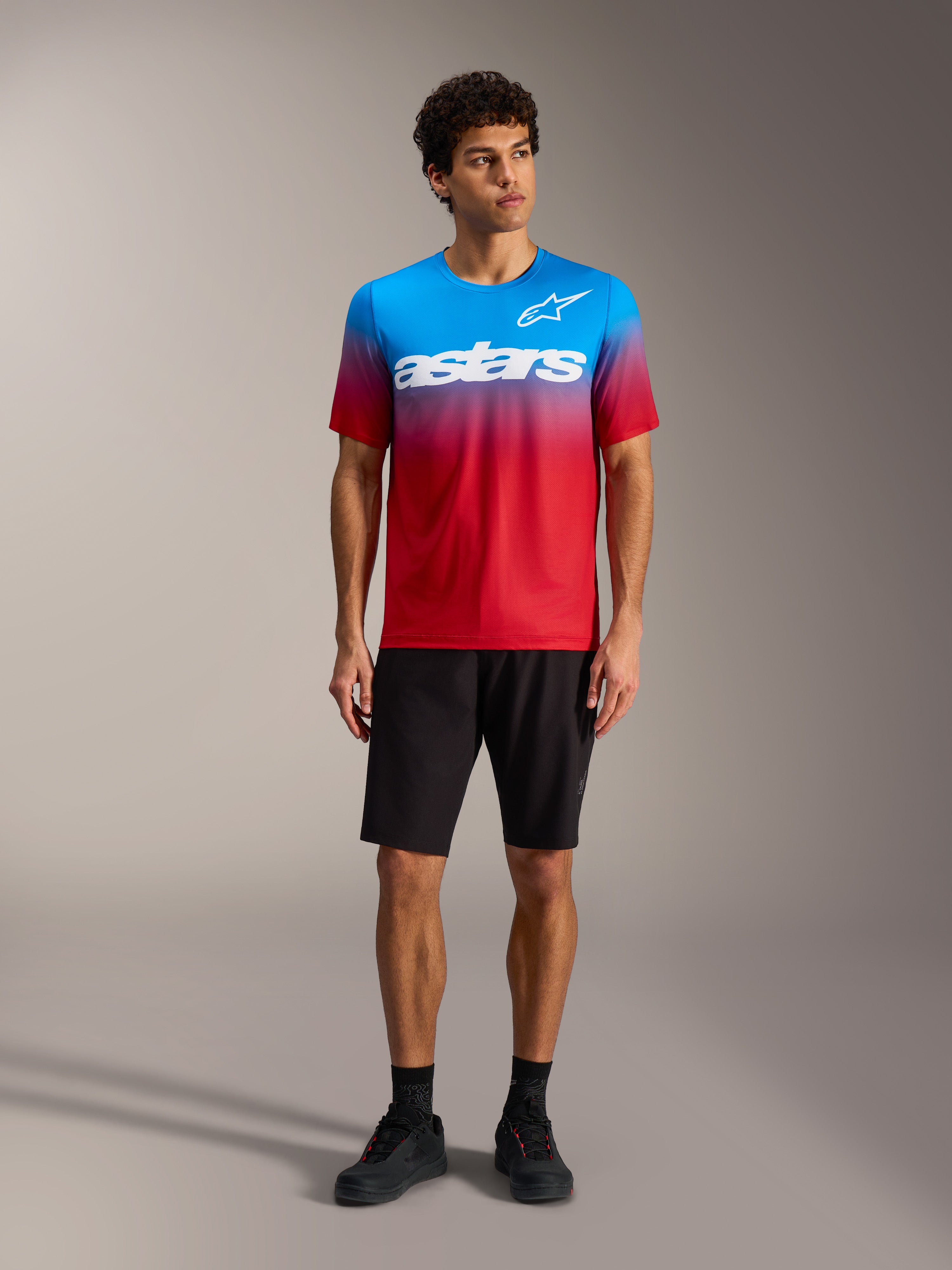 A-Dura ASTARS Jersey 2.0 in Hellrot-Blau mit weißem Logo, kombiniert mit schwarzen MTB-Shorts und Schuhen.