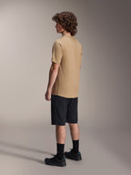 Alpinestars A-Dura Liner Shorts in Schwarz und A-Dura SS Jersey in Tan, getragen von einem männlichen Model in der Seitenprofilansicht, kombiniert mit schwarzen Socken und Radschuhen, Mountainbike-Lifestyle-Bekleidung.