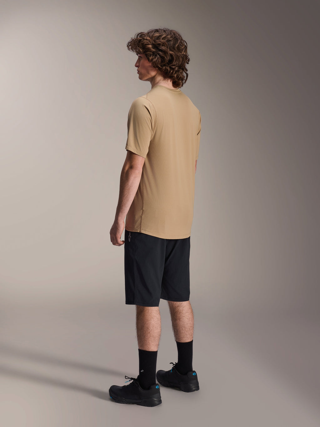 Alpinestars A-Dura Astar Kurzarm-Trikot, Hellbraun, getragen mit schwarzen Shorts und schwarzen Socken, feuchtigkeitsableitendes Jacquard-Gewebe, lässige Mountainbike-Performance-Bekleidung
