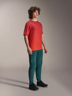 Alpinestars A-Dura Rise Kurzarmtrikot, Spicy Orange, mit kleinem schwarzen Brustlogo, getragen mit dunkel-petrolfarbener Hose und schwarzen Schuhen, leichte feuchtigkeitsableitende Mountainbike-Bekleidung.