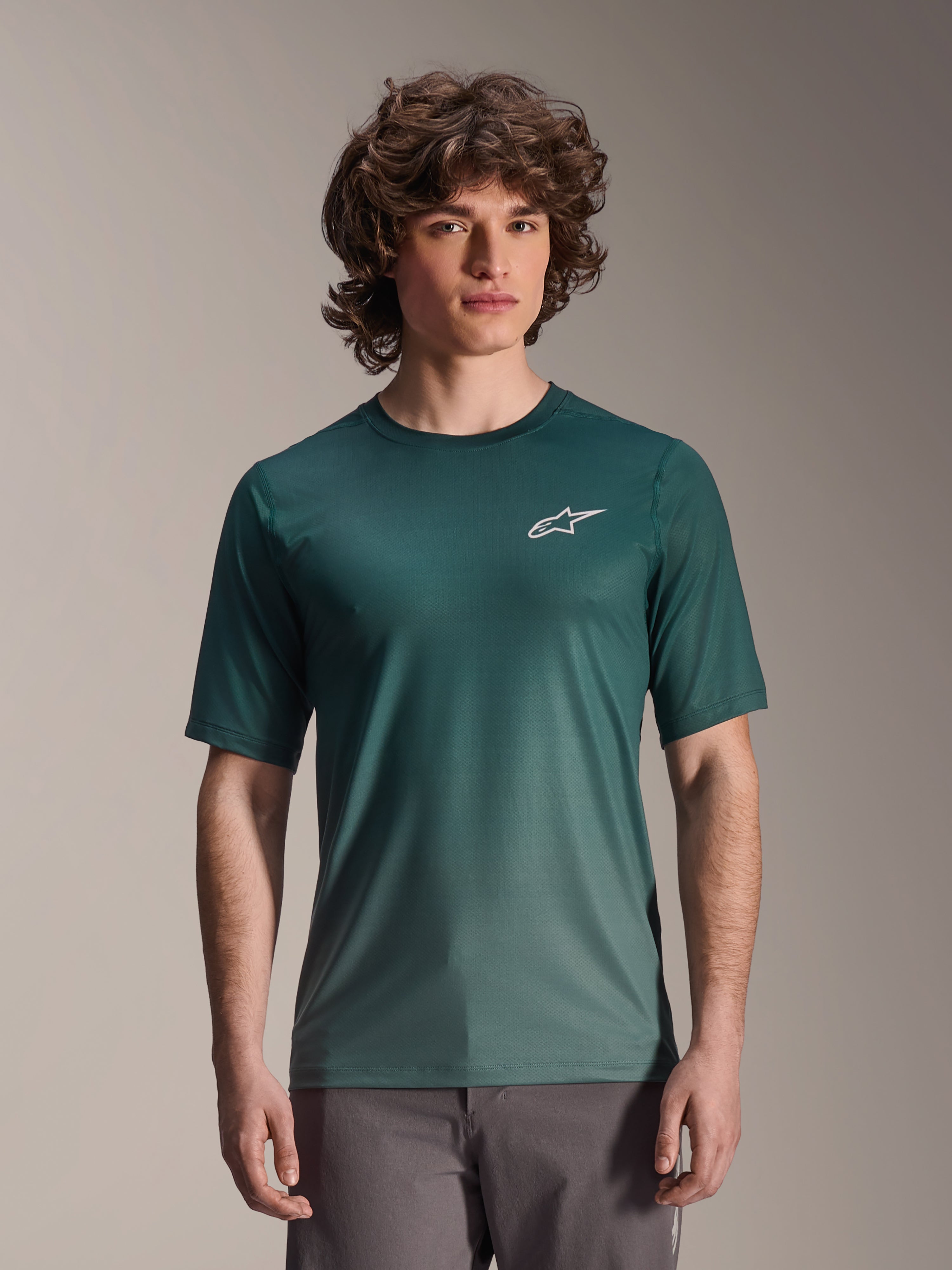Alpinestars A-Dura Rise Kurzarm-Trikot, Silver Pine Dunkelgrün, von einem Model getragen, mit einem weißen Astars-Logo auf der Brust, leichtes feuchtigkeitstransportierendes Jacquard-Gewebe, lässiges Mountainbike-Performance-Shirt