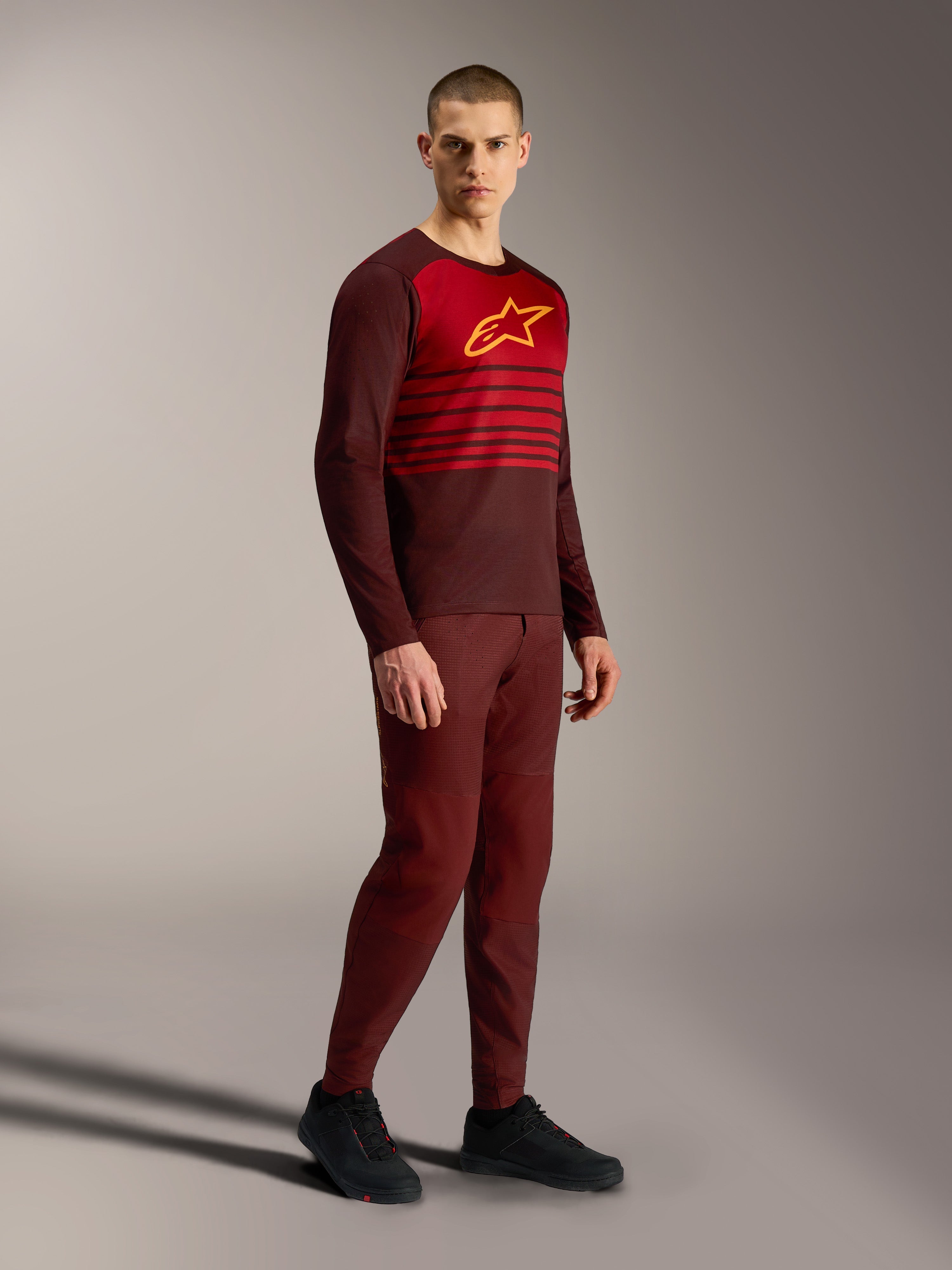 Alpinestars A-Dura Elite Trikot 2.0, bordeauxfarbenes Langarm-MTB-Jersey mit rotem Brustbereich und gelbem Logo.